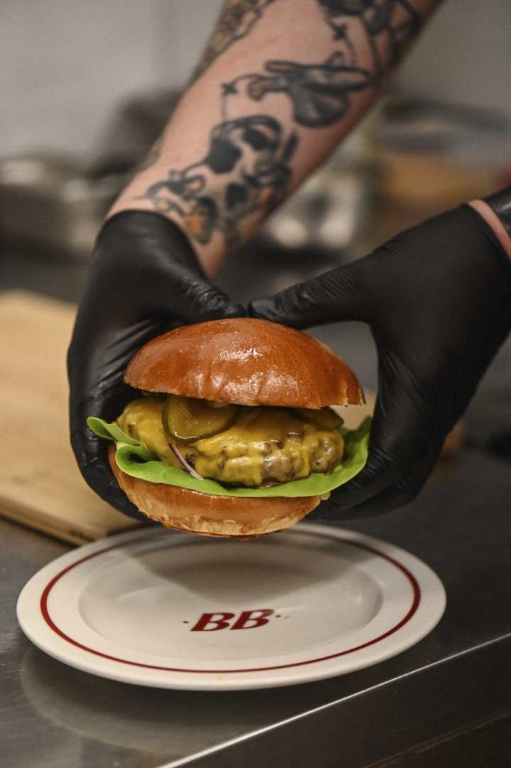 Szef kuchni trzyma burgera nad talerzem BB