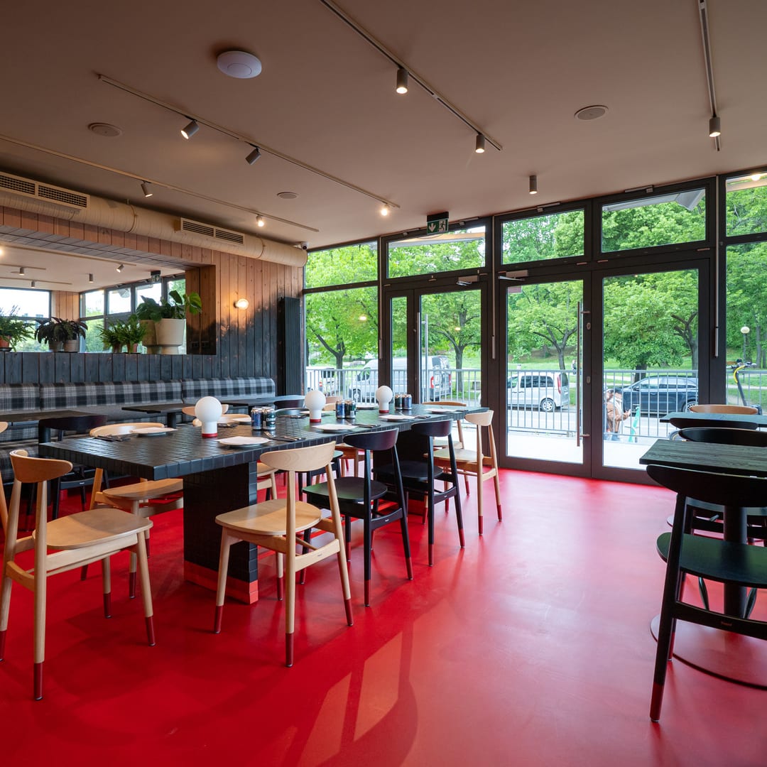 Sala restauracji z czerwoną podłogą i widokiem na park